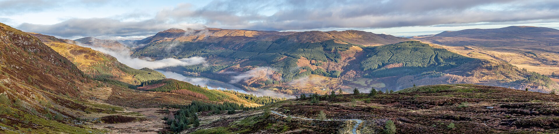 Scottish landscape of mountatins around a glen, Loch Lubnaig is in the base of the glen surrounded by mist and clouds.