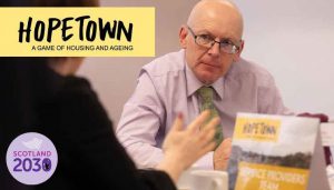 Photo of older man listening with text on top: "Hopetown - a game of housing and ageing"