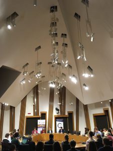 Photo of event with people sitting around a committee room table in the Scottish Parliament