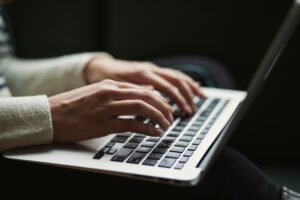 Close-up photo of hands typing on a laptop
