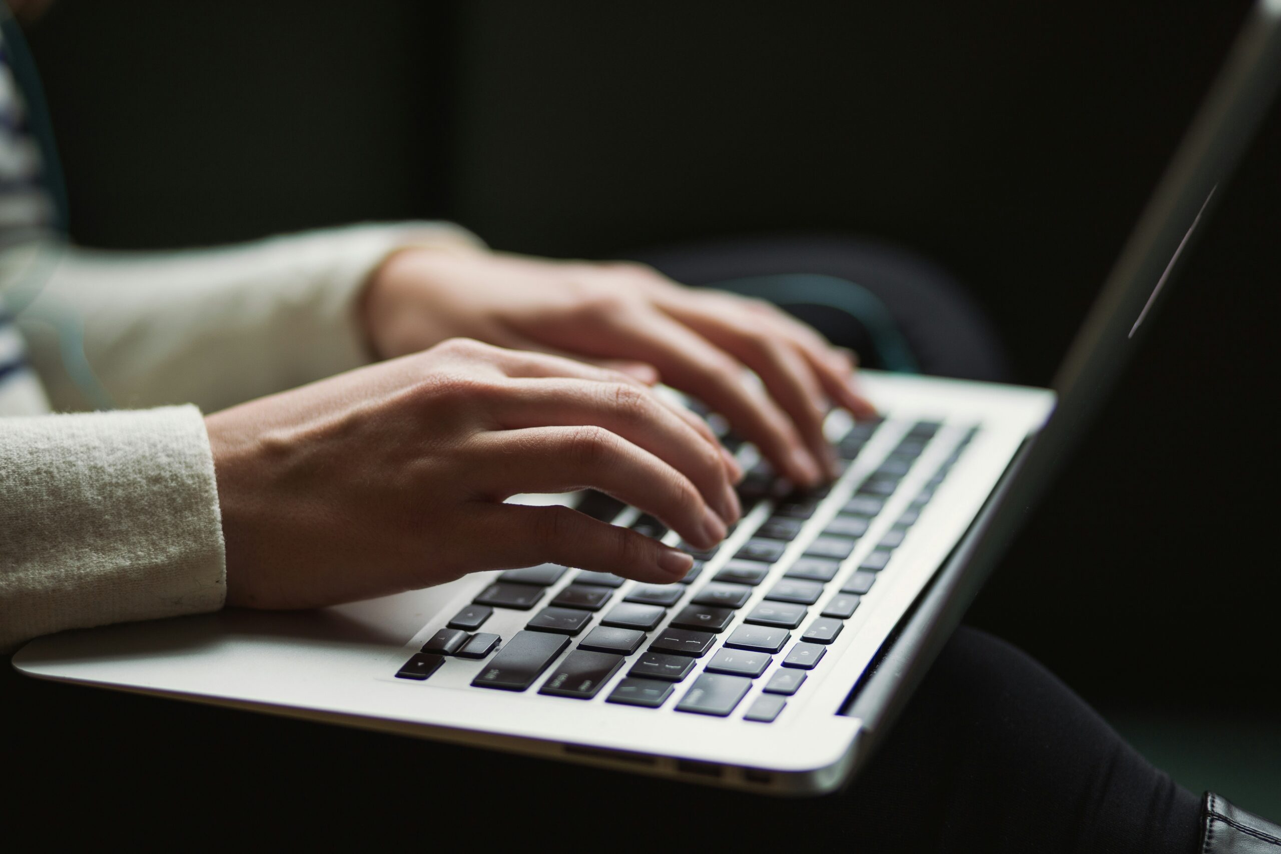 Close-up photo of hands typing on a laptop